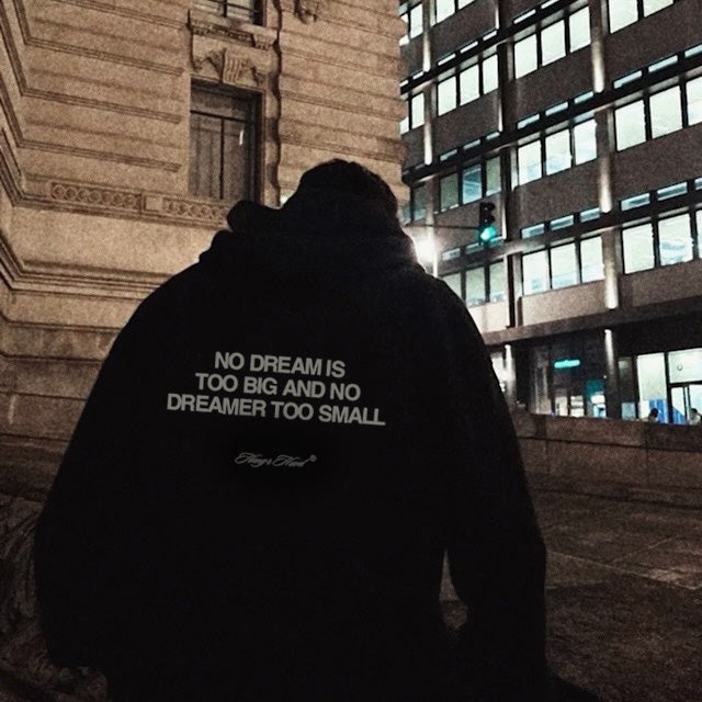 Person wearing a hoodie with text in an urban night setting